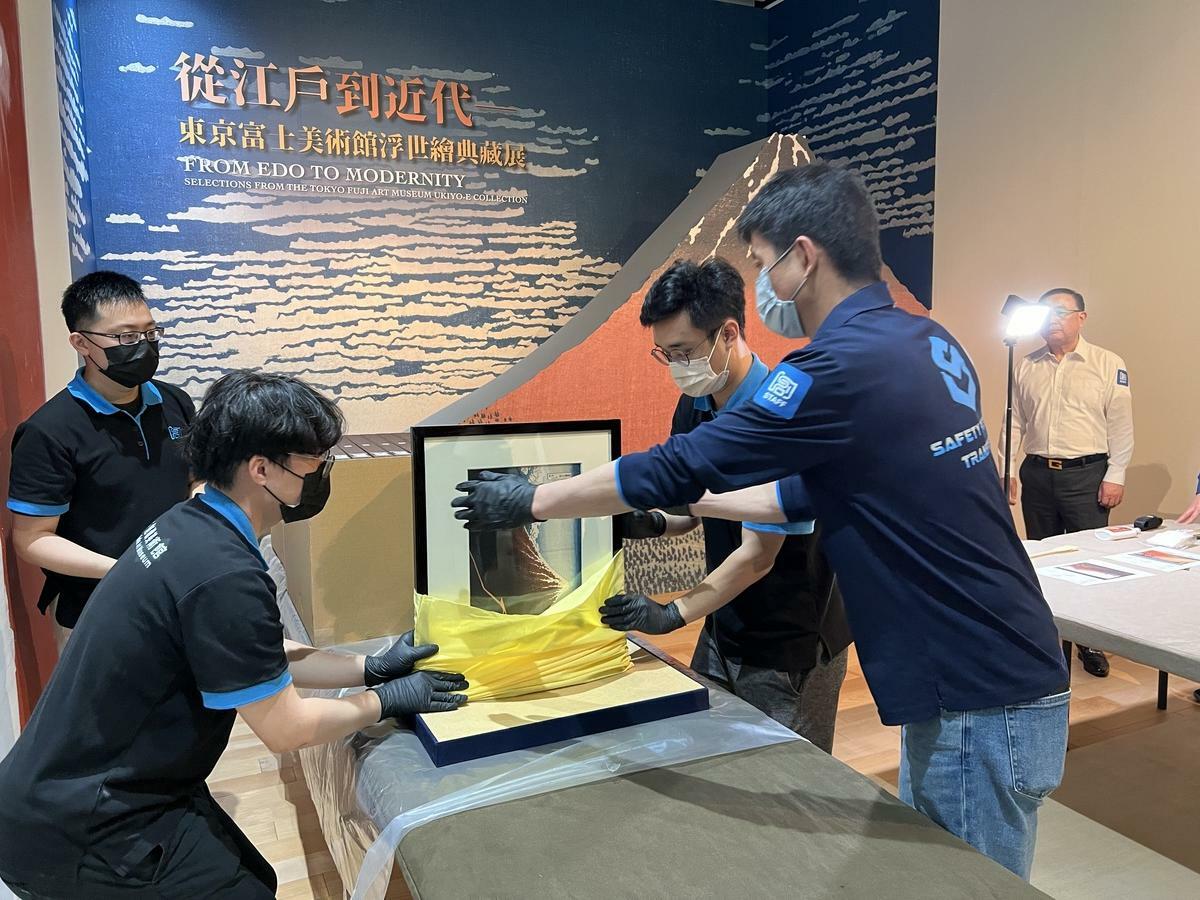 布展團隊取出展覽作品〈富嶽三十六景 山下白雨〉。 圖：創價美術館/提供