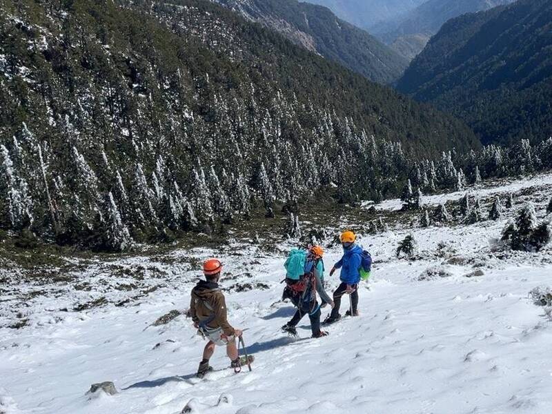 玉山主峰往北峰的叉路碎石坡有男女山友墜落380公尺深谷遭雪埋身亡，救難人員在雪地中協助搬運遺體。 圖：玉管處提供