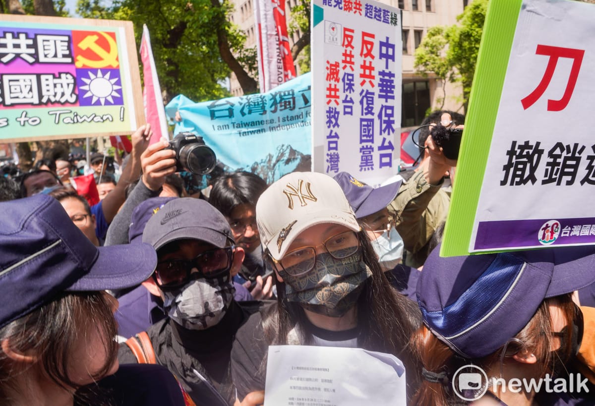 亞亞（前戴白帽）日前赴內政部前開記者會，有民眾高舉台灣獨立旗、有的高舉「外抗共匪 內除國賊」、「反共保台」等標語，表達對亞亞的不滿。 圖：張良一/攝