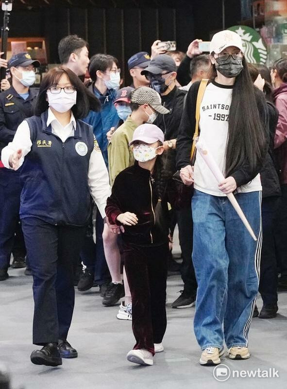 陸配亞亞遭廢止依親居留許可，25日限期前自松山機場出境。在移民署官員陪同下，牽小女兒走向航空公司櫃檯。 圖：張良一/攝