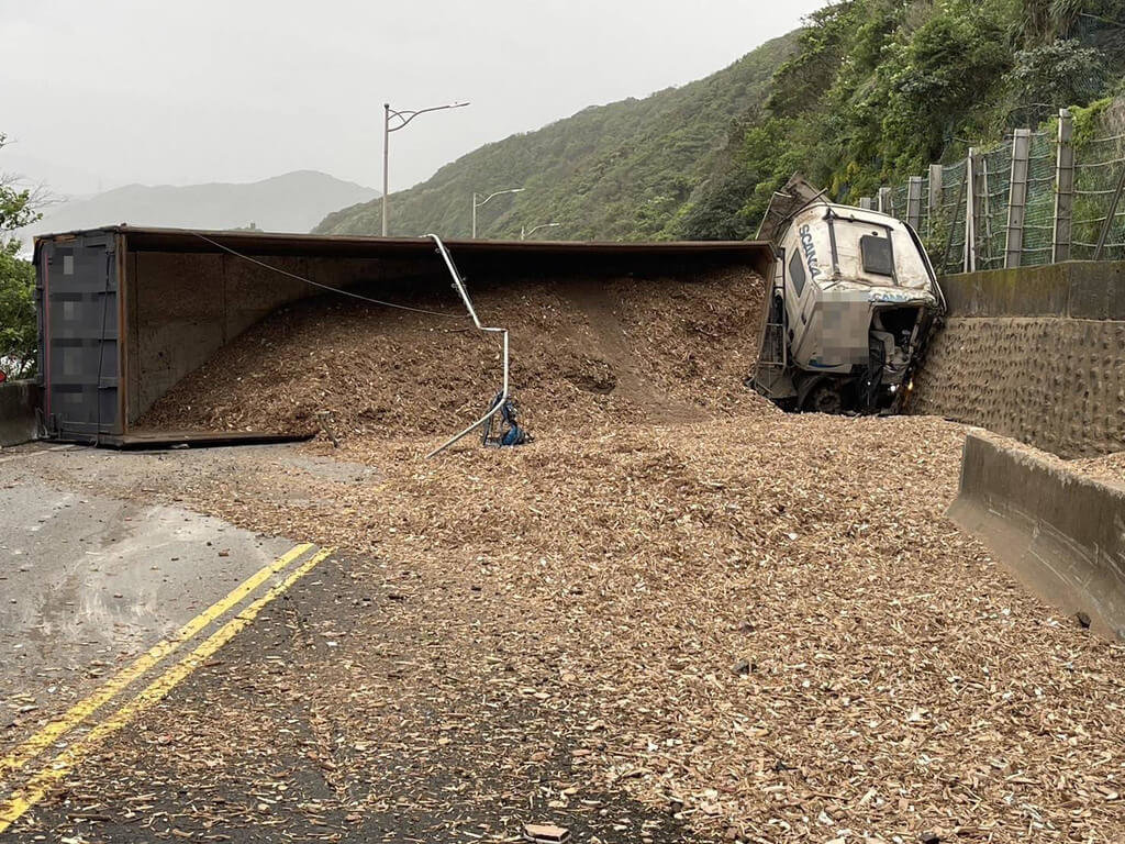 楊姓男子13日清晨駕駛曳引車，沿新北市瑞芳區台2線88公里處基隆往宜蘭方向行駛時不慎翻覆，車上載運的木屑散落路面，幸楊男意識清楚、僅受輕傷。 圖/中央社(讀者提供)