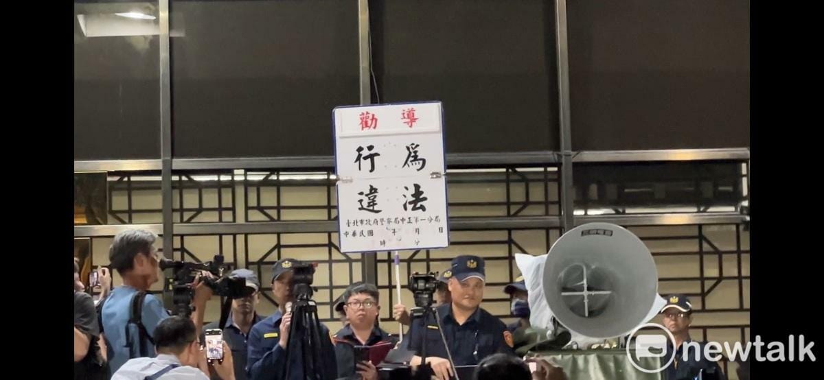 在國民黨主席朱立倫號召下，大批支持者晚間聚集北檢抗議司法不公。中正一分局舉牌警告行為違法。 圖：張良一/攝