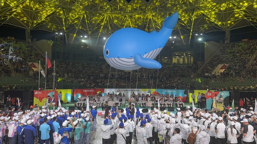 114年全國中等學校運動會19日晚間在台南市盛大舉行開幕典禮，鯨魚造型吉祥物「鯤鯓」的大型氣球在眾人牽引下飄過主舞台前，十分吸睛。中央社記者張榮祥台南攝  114年4月19日