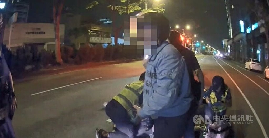 台中李姓男子21日凌晨身體不適，由李母（前）騎機車載送要到醫院掛急診，行經大里區德芳南路近大里路口時，李男突然摔落機車無呼吸心跳，李母報案後，消防人員與警方到場處理。 圖：中央社（翻攝照片）
