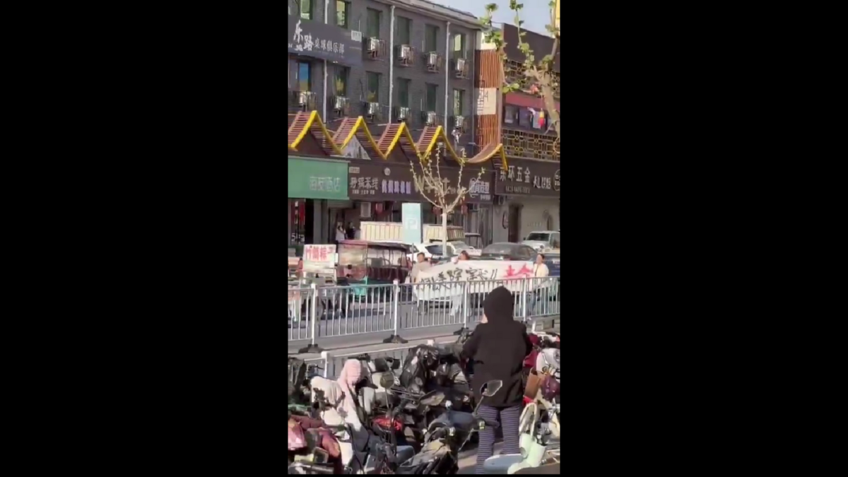 數名家長在街上拉著白色橫幅，橫幅上寫著「河北美院害我兒喪命」，表達對校方的不滿與控訴。 圖:翻攝自影片