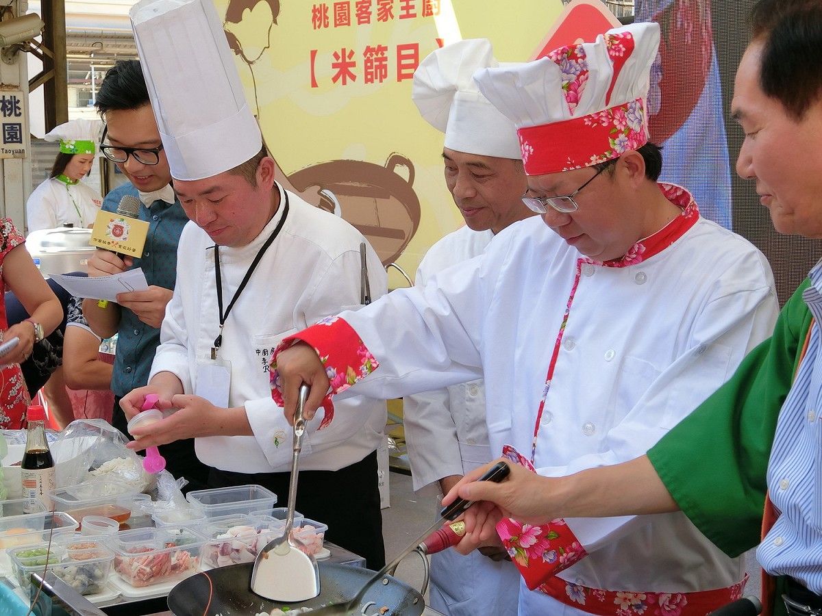 鄭文燦當大廚，捲袖炒海鮮米苔目給香川縣知事濱田惠造吃，且不忘貼心照顧這位不懂中文的姐妹市市長。 圖：李書璇/攝