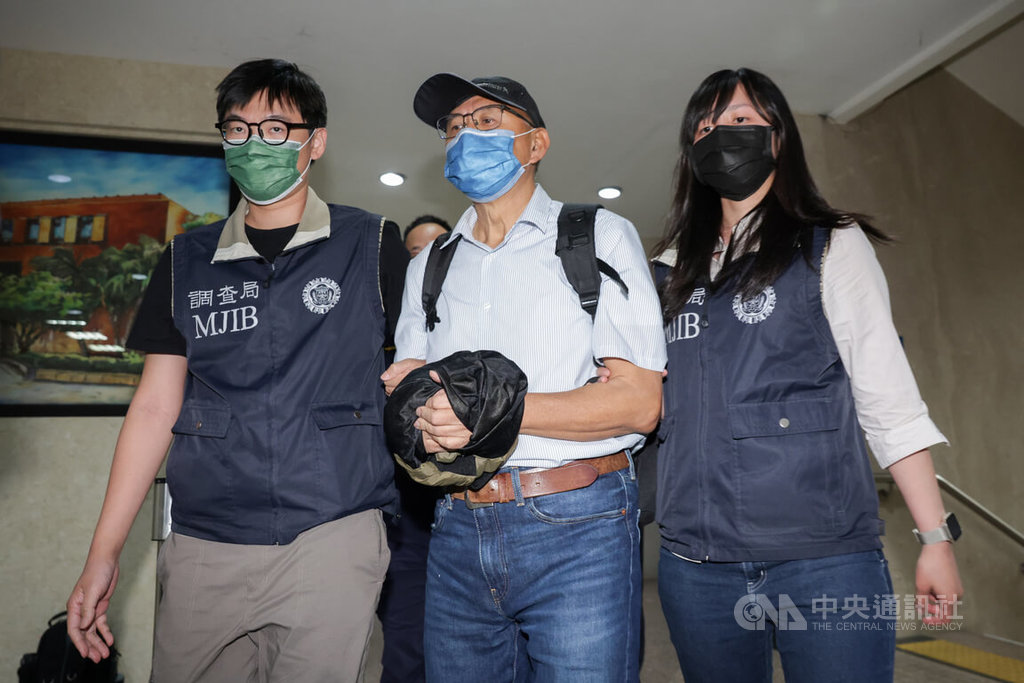 台北地檢署偵辦國民黨立委傅崐萁競選小物案，通緝中的被告李慶隆（中）9日主動向檢調投案，調查局北機站晚間將李慶隆解送北檢歸案，李慶隆戴著口罩、帽子，雙手上銬處則以衣物遮擋。中央社記者裴禛攝  114年5月9日