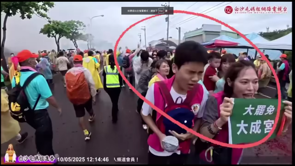 一名婦人高舉「大罷免 大成宮」布條跪於鑾轎前，媽祖鑾轎行至其前方時突然緊急煞車並倒退，旋即轉向快速離開，現場信眾錯愕不已。 圖:翻攝自臉書Lu編噹時事