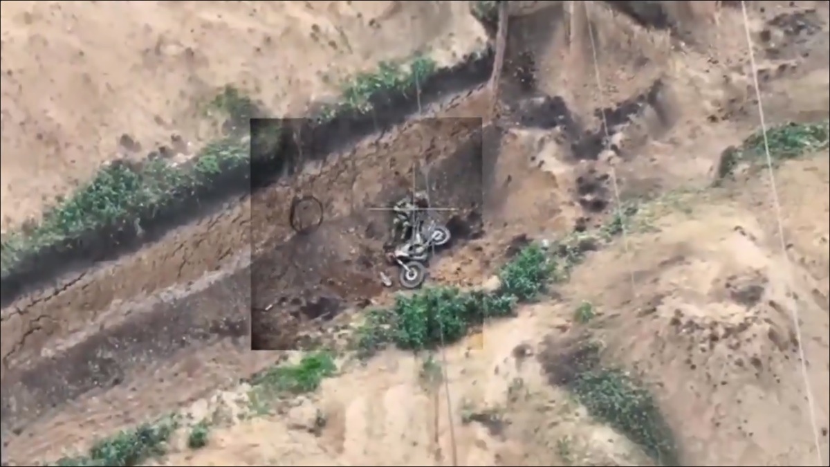 一名俄軍士兵試圖騎著摩托車躲進壕溝中，但卻在抵達前摔車躺倒在地上。 圖：擷取自 @NOELreports X 分享影片