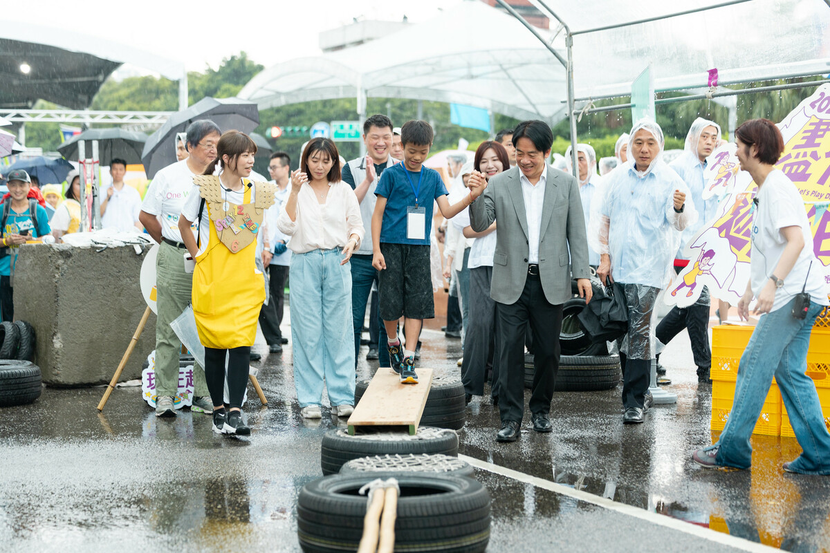 賴清德在雨中與孩童一起遊戲。 圖：總統府提供