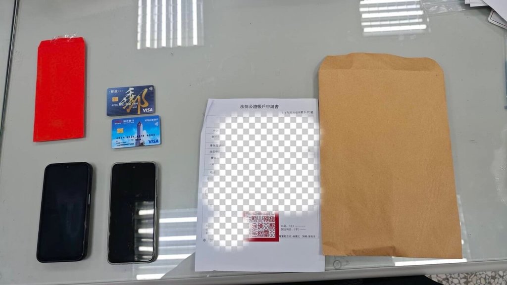 台中市警察局第二分局立人派出所員警日前執行巡邏勤務時，發現1名形跡可疑男子正與婦人交換牛皮紙袋與紅包袋，警方進一步查證後，確認男子假冒檢警人員進行詐騙，當場逮捕這名馬來西亞籍的面交車手，並查扣手機、金融卡及法院公證本票等贓證物。（民眾提供）中央社記者郝雪卿傳真  114年6月15日