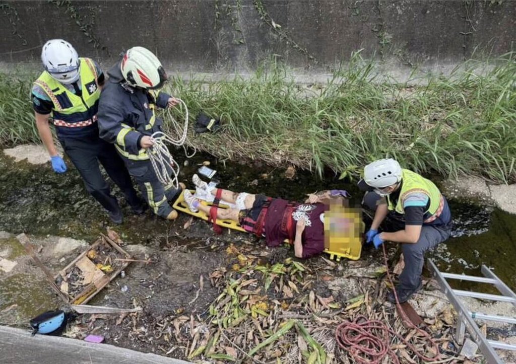 1名婦人23日上午騎機車行經彰化市石牌國小時疑似恍神摔車，不小心摔入路旁約2公尺深大排水溝，警消獲報趕到現場，消防隊員用擔架救出婦人。（消防局提供）中央社記者吳哲豪傳真 114年6月23日