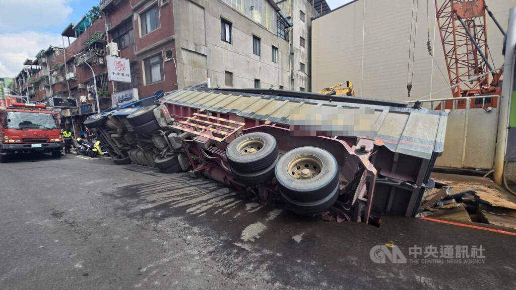 新北市三重區龍門路一處工地前路面26日塌陷，造成一輛停放路旁的砂石車側翻，消防獲報前往救援，幸無人受傷。（翻攝畫面）中央社記者趙敏雅傳真  114年6月26日