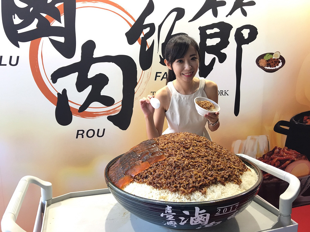 2017台灣滷肉飯節巡迴列車今(15)天抵達有百年歷史的台中第二市場，現場展示出超巨大200人份滷肉飯，跟正妹手裡拿的「正常版」尺寸相較，簡直是螞蟻與大象！ 圖：台中市政府經發局/提供