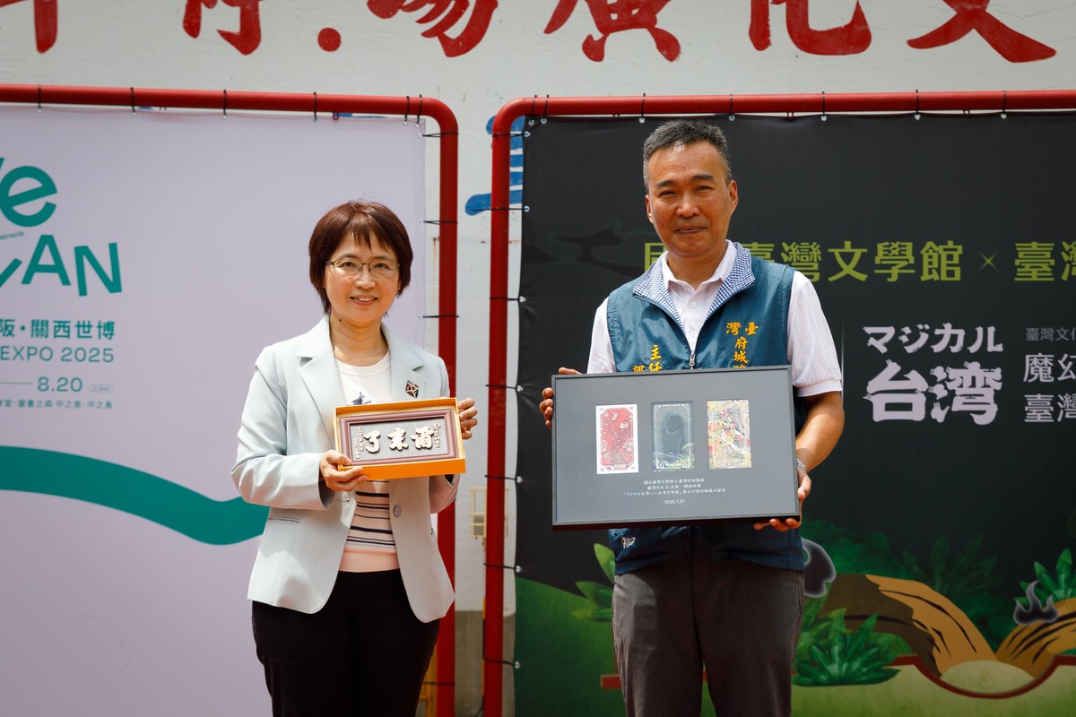 台文館陳瑩芳館長（左）手持府城隍廟郭榮哲主委致贈「爾來了」牌匾、郭榮哲（右）手持台文館回贈「魔幻台灣」特展書籤。 圖：台灣文學館提供
