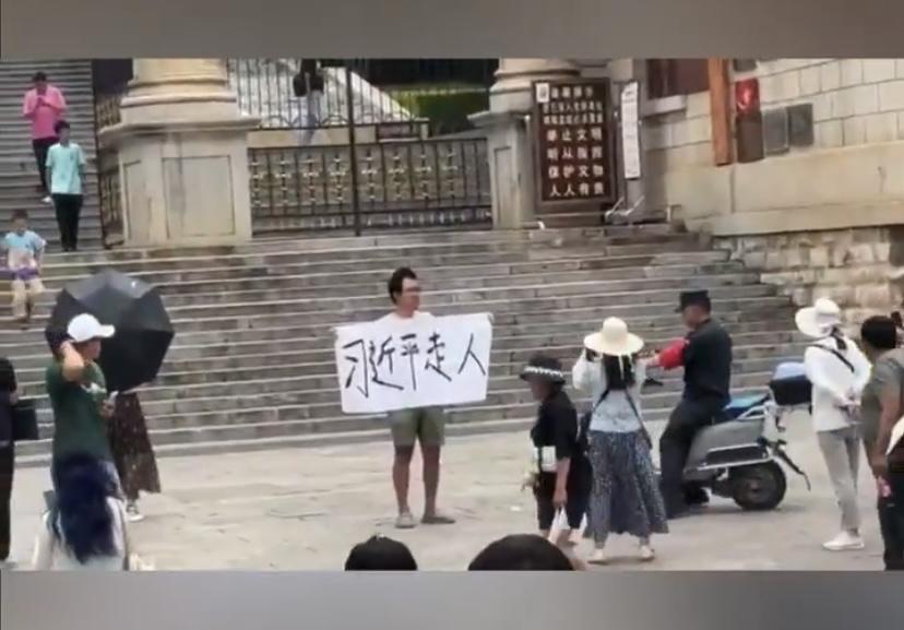 昆明市的勇士廣場出現一名民眾公開舉牌要求「習近平走人」。 圖：翻攝自 X