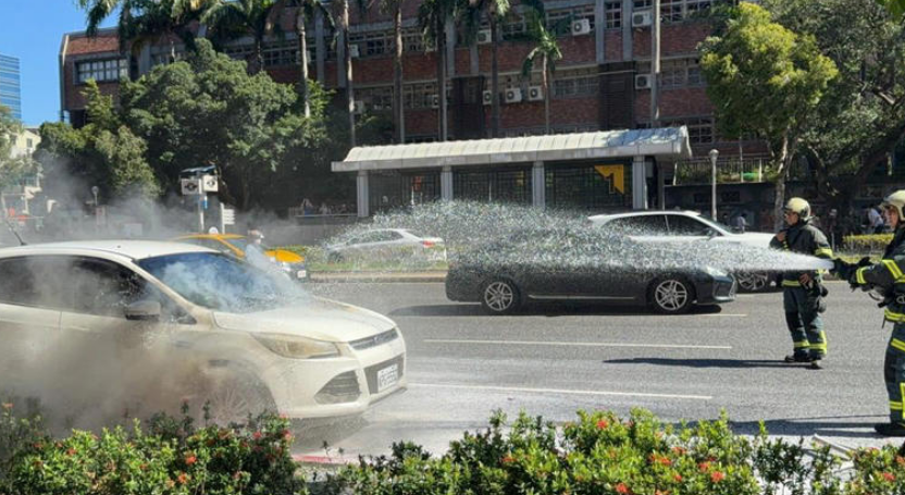 白色休旅車因不明原因突然冒煙起火，消防單位緊急佈水線灌救。 圖：民眾提供