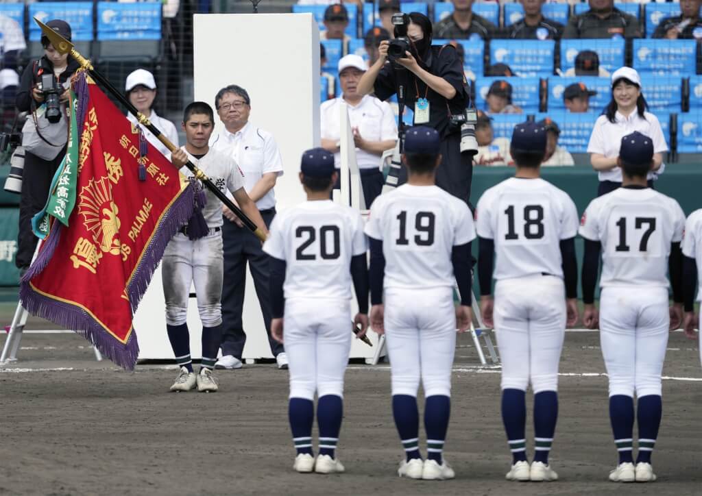 沖繩尚學隊長真喜志拓斗接過冠軍旗。（共同社）