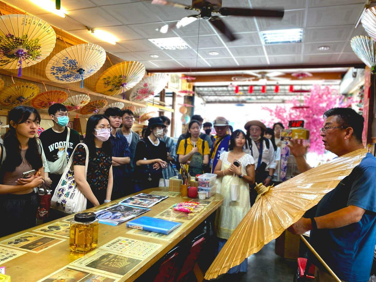 李家紙傘李明祥老師(右一)向學員講解美濃客家紙傘的歷史淵源及象徵意義。 圖：高雄市青年局/提供