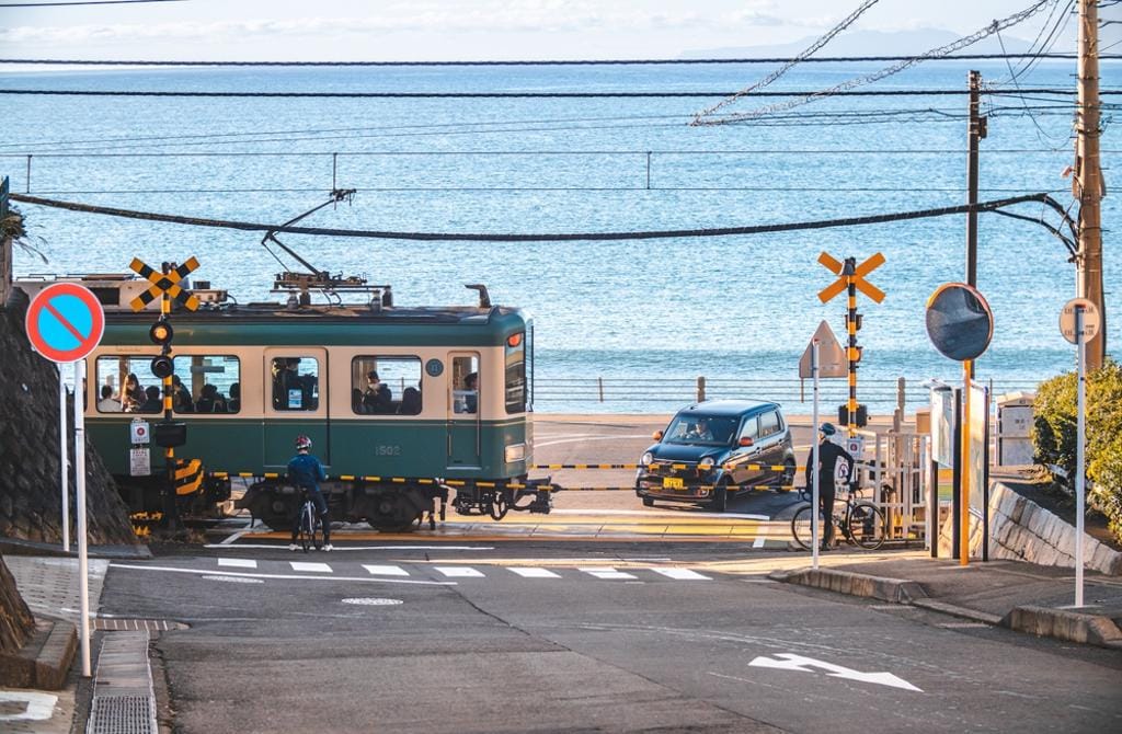 因為日本漫畫《灌籃高手》的關係，各國旅客湧入鎌倉市的鐵道平交道，搶著與列車及海景合照，深深地影響當地居民的生活。 圖：擷取自 shutterstock
