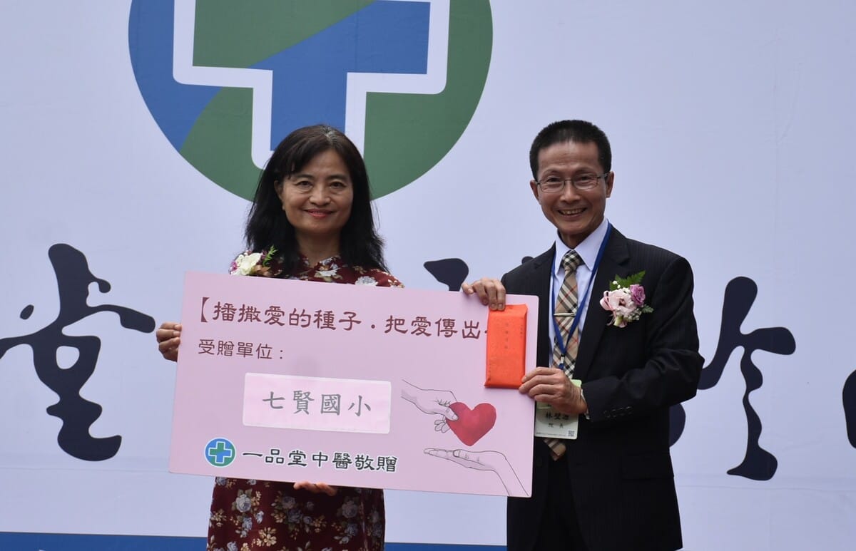 七賢國小校長楊勝任(左)代表接下「一品堂中醫」捐助的善款。 圖：孫家銘攝