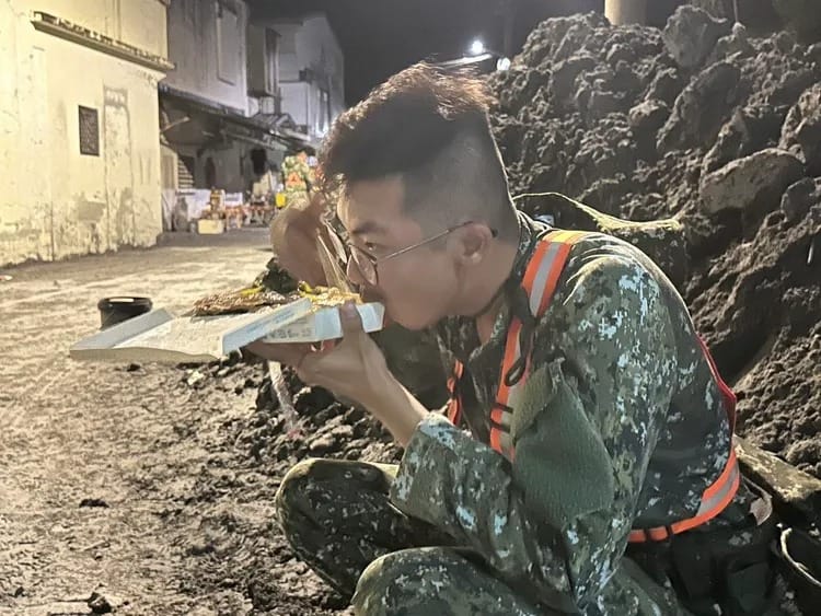 國軍弟兄徹夜協助災區復原，蹲在爛泥中吃便當畫面令人揪心。 圖：軍方提供