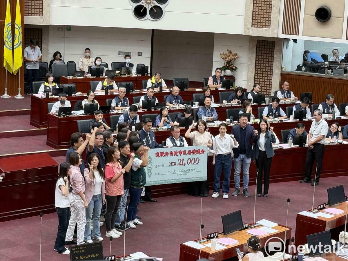 民進黨台北市議會黨團致贈上方寫著「2.1萬元」的大型支票給市長蔣萬安，呼籲還稅於民、普發現金。 圖：周煊惠 / 攝