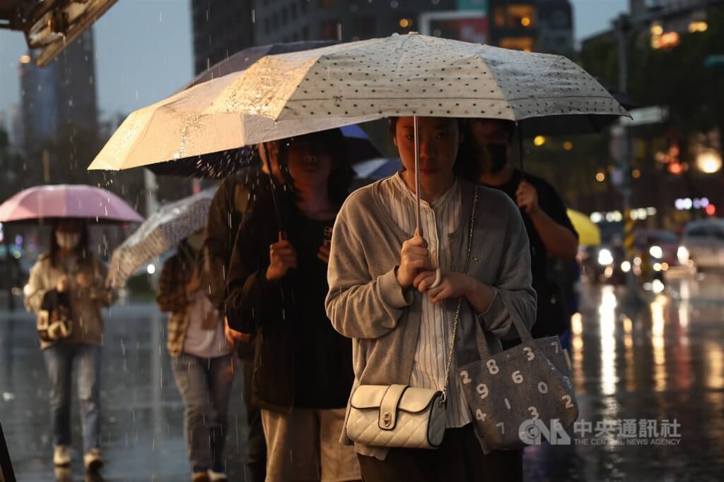 圖為新北市板橋區降下大雨，街上行人撐傘走避。（中央社檔案照片）