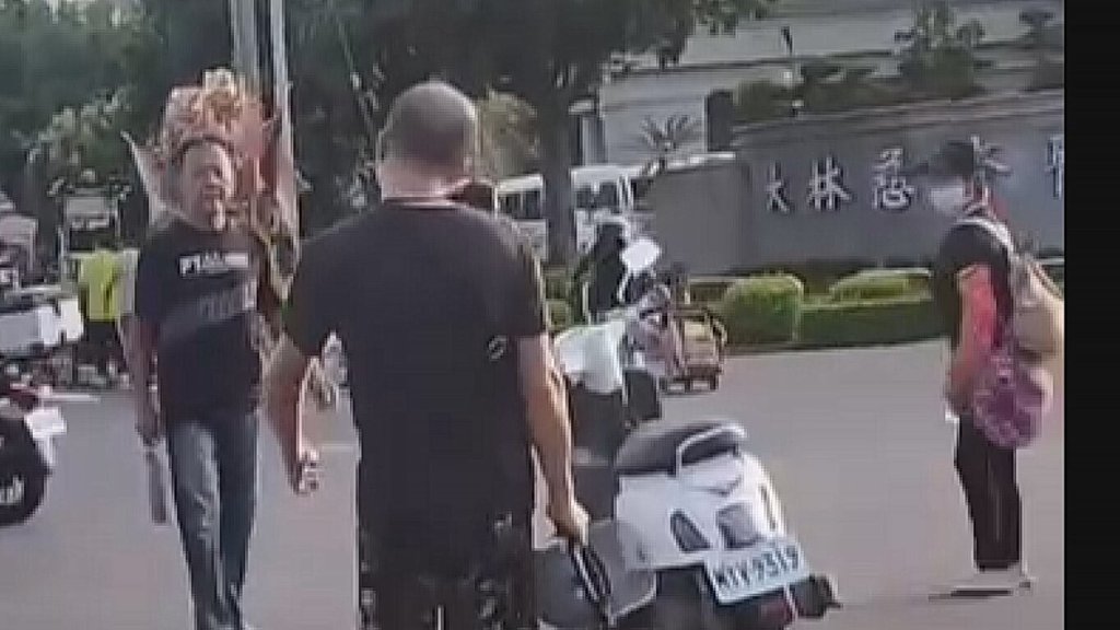 嘉義縣某宮廟繞境隊伍11日下午行經大林慈濟醫院旁時，突有一名酒醉男子（左）持刀混入隊伍中，意圖傷人。（民眾提供）中央社記者蔡智明傳真　114年10月14日
