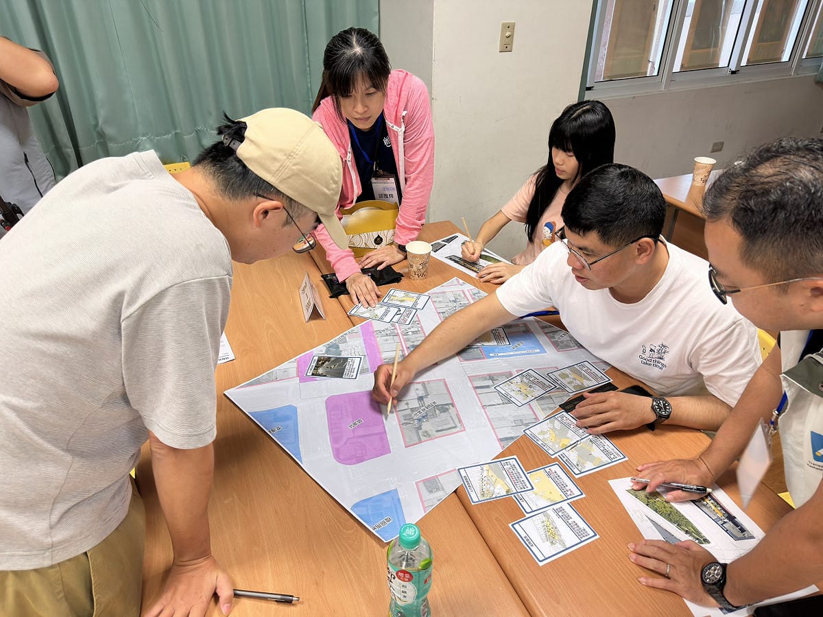 居民圍繞街區圖面動手畫街道，討論人行空間、停車與裝卸貨需求，將生活經驗轉化為規劃建議。 高雄市政府交通局廣告