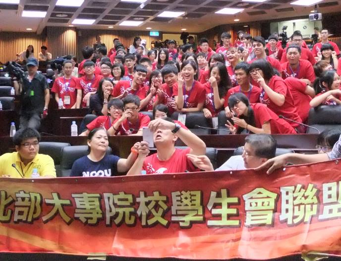 台北市長參選人連勝文今(18)日出席北區大專院校學生會幹訓課程，並穿著和學生一樣的紅色營服，一一和現場學生握手，甚至拿出自己的手機和學生們自拍合照。圖：陳思穎/攝