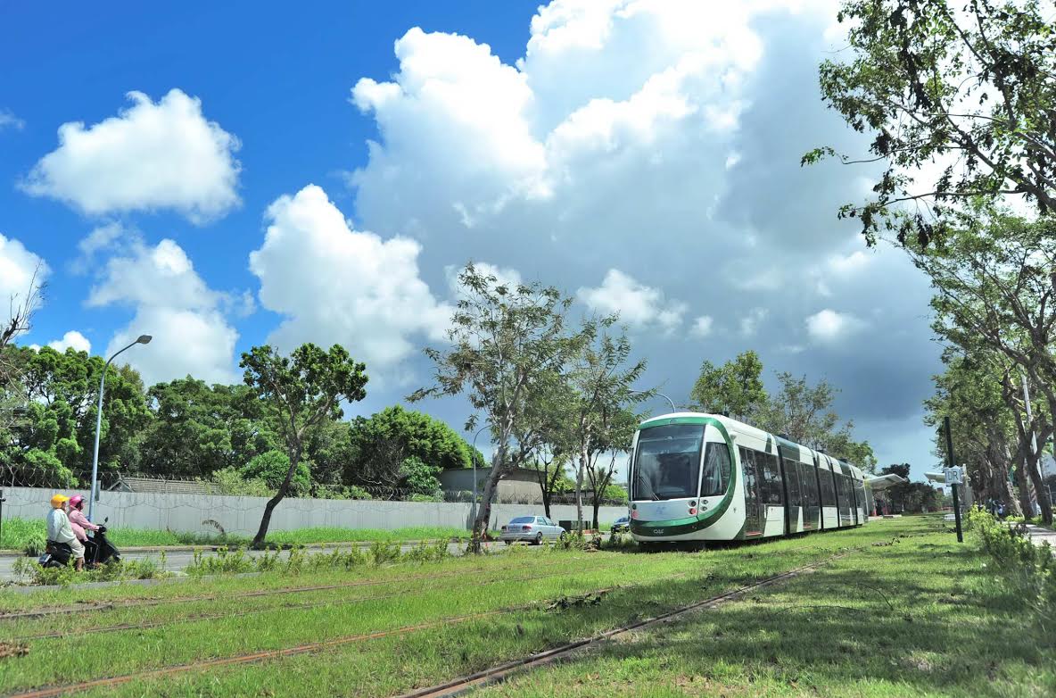 輕軌上路象徵高雄在綠能公共運具、節能減碳大躍進，輕軌列車穿捘綠意盎然的市區道路，頻添高雄都市風情。圖：高雄市政府提供