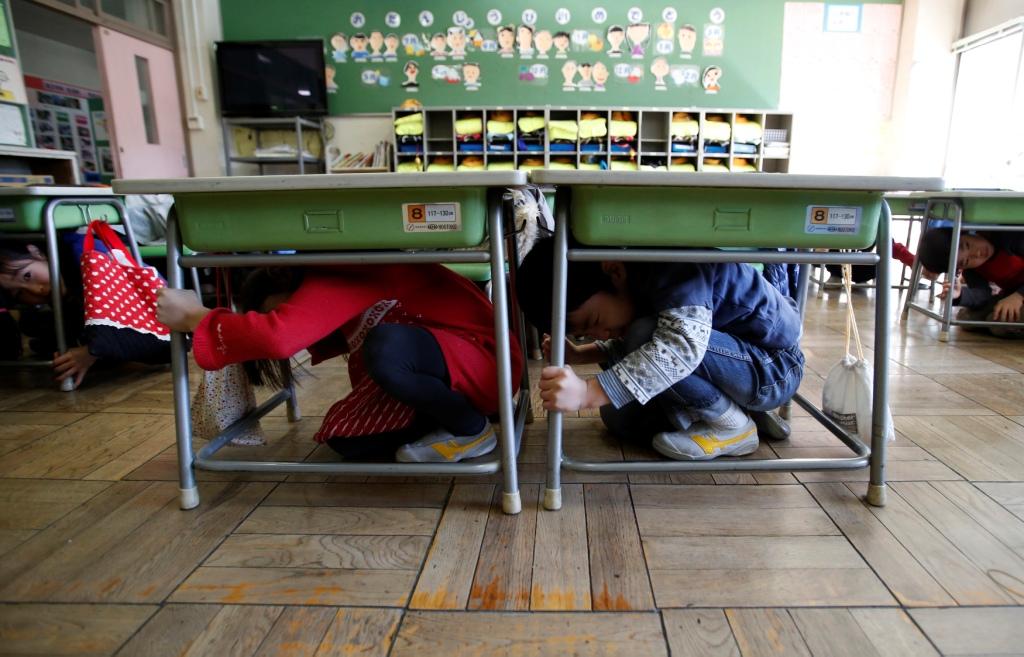 日本東北地區今(12)日淩晨4點22分左右，發生6.8級地震。圖為今年3月11日，日本小學生學習在地震來臨時如何躲在桌椅下避難。圖片來源：達志影像/路透社