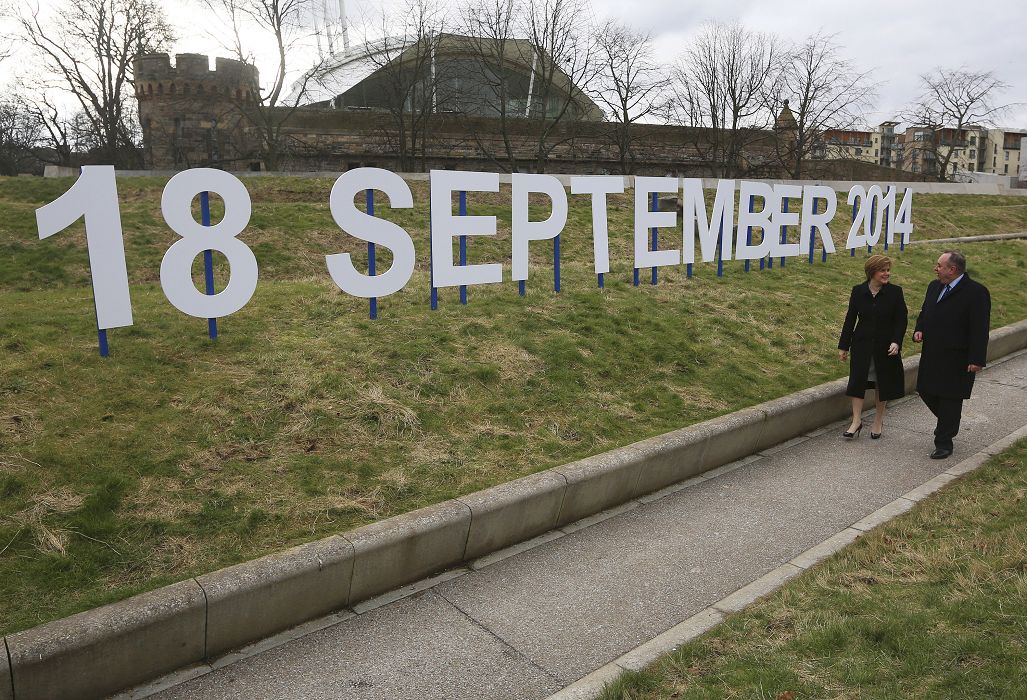蘇格蘭地方政府首席部長、蘇格蘭民族黨領袖薩蒙德(Alex Salmond)21日走在蘇格蘭議會外，旁邊豎立著獨立公投時間的字牌。圖片來源：達志影像/路透社。
