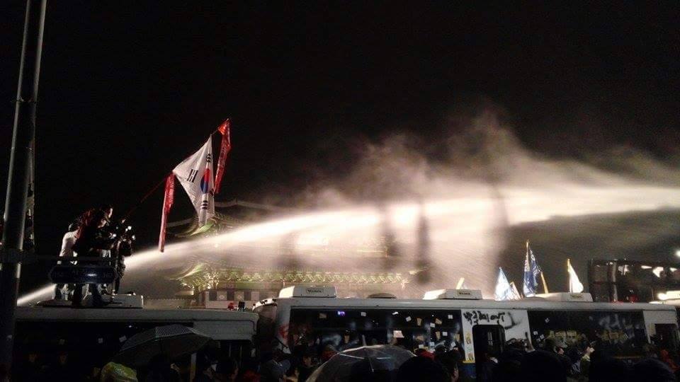 世越號罹難者家屬18日晚間赴總統府遊行並爆發衝突，警方則動用大型水柱朝示威者噴灑，試圖驅散人群。圖：翻攝自韓半島新聞平台臉書
