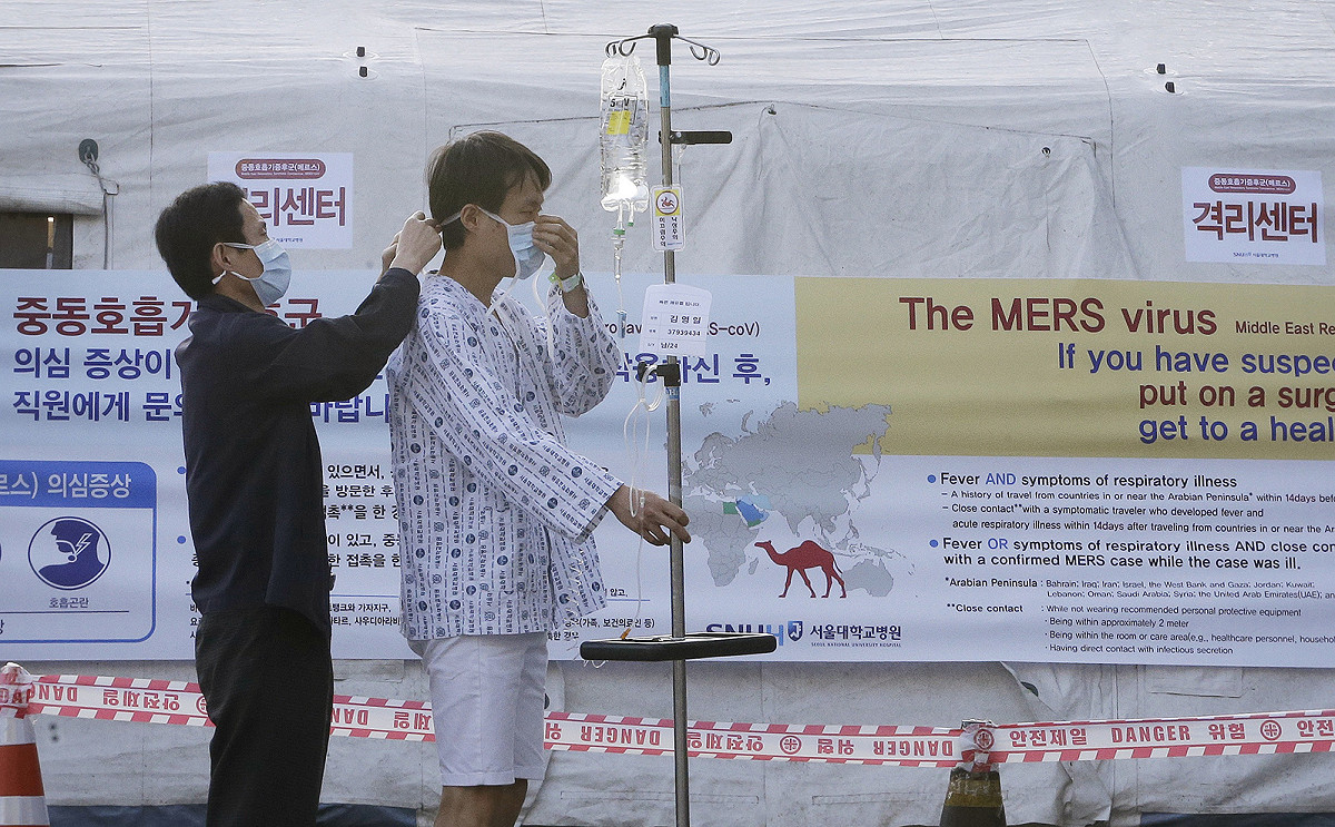 據韓國保健福祉部21日通報，新增3起中東呼吸症候群（MERS-CoV）確診病例。圖為1名醫護人員正幫病患戴立口罩，醫院走道也貼滿韓文及英文警示標誌，提醒防範MERS感染。圖片來源：達志影像/美聯社資料照片