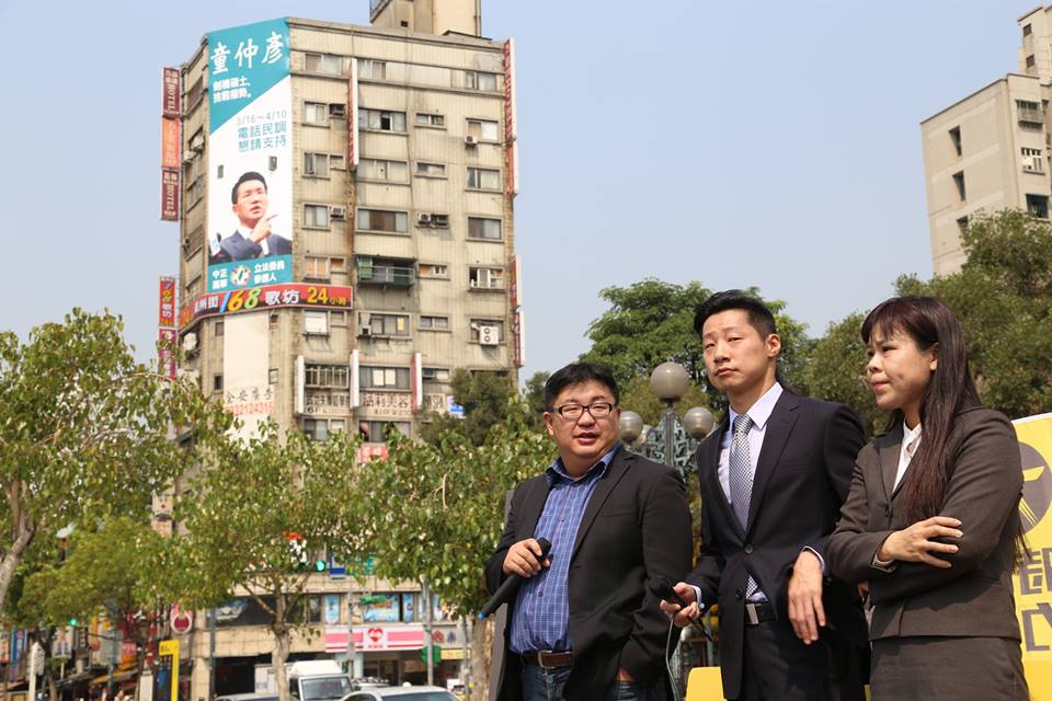在時代力量今(19)天在龍山寺召開記者會的現場路口後方，就貼著民進黨市議員童仲彥參選立委，懇請支持民調的巨幅廣告。圖：林雨佑/攝
