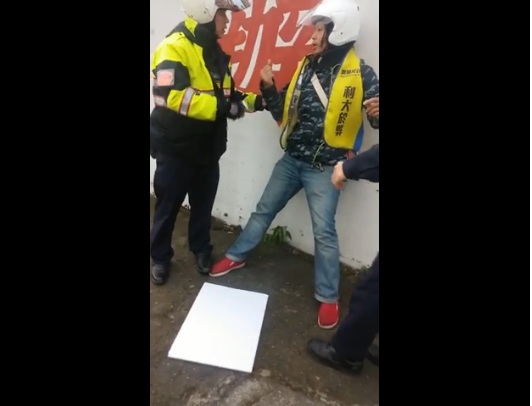上午割闌尾志工在街頭舉牌，遭到警方強制押回。圖：翻攝youtube