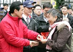 總統馬英九（左）23日大年初一赴台北市保安宮參拜，並發放金龍福袋，現場民眾依序排隊，向馬總統索取福
袋討吉利。圖片來源:中央社