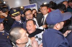 中國富豪陳光標26日晚間率團搭機抵台，民進黨籍桃園縣議員廖輝星（中）等人前往抗議，遭航警層層戒護隔離，場面混亂。圖片來源：中央社