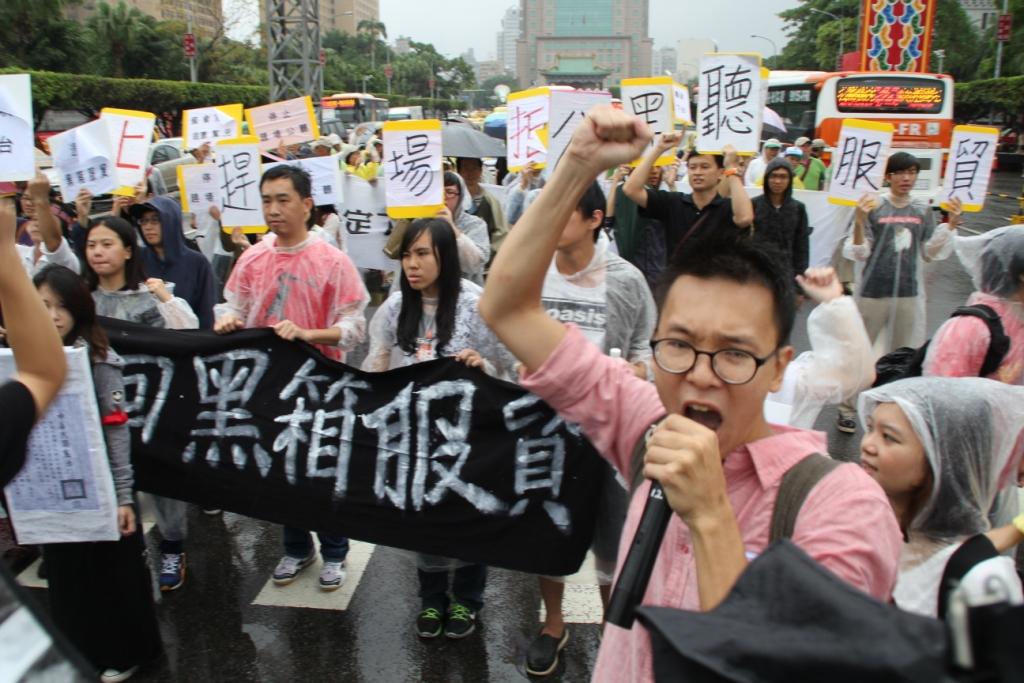 數十名學生從立法院轉往總統府前抗議，高喊口號「停止趕場公聽、退回黑箱服貿」。圖：林雨佑/攝
