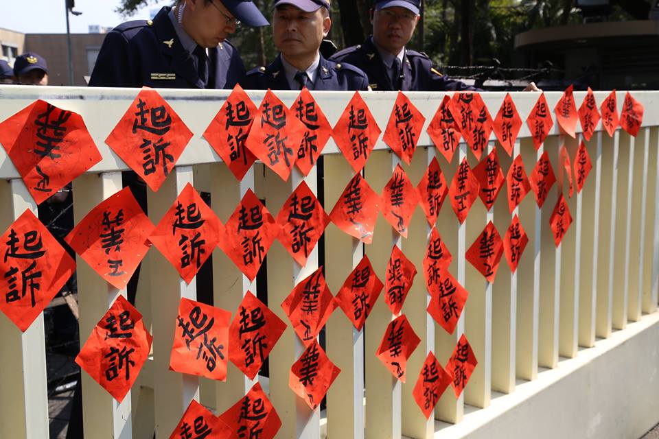 太陽花學運遭起訴的人士12日將手上的「起訴」和倒貼的「正義」春聯貼在行政院的圍欄上，象徵人民也要正式起訴政府。圖2之1：林雨佑/攝