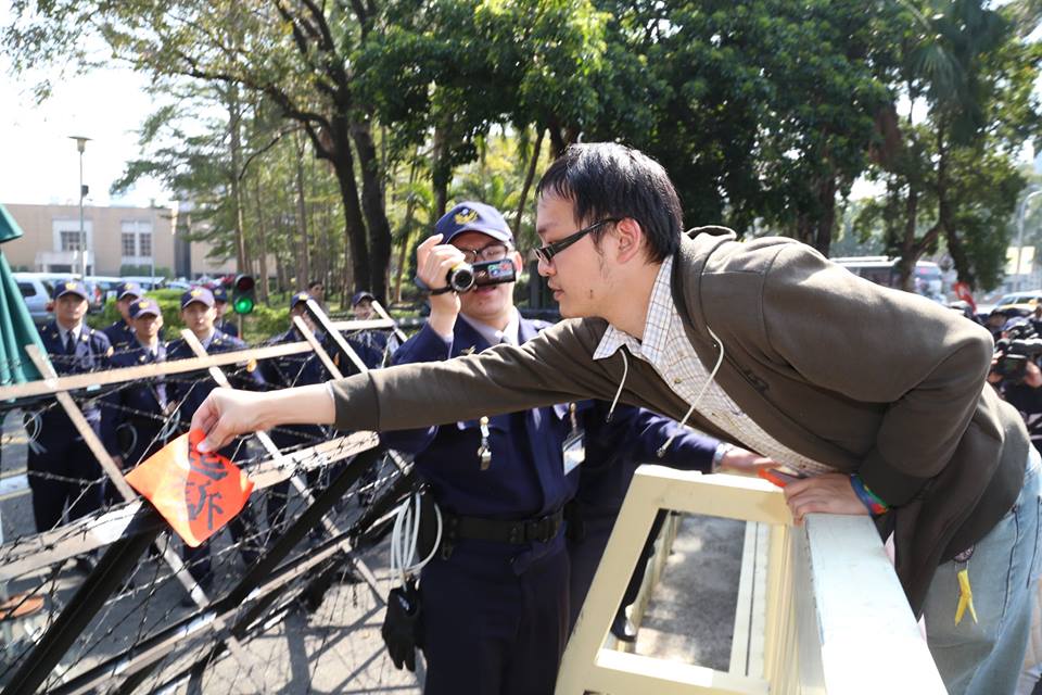 因411路過中正一分局遭起訴的洪崇晏伸出上半身，把春聯貼在圍欄後的拒馬上。圖2之2：林雨佑/攝