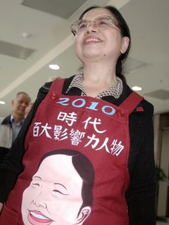 前往美國接受時代雜誌百大影響人物獎項的台東菜販陳樹菊女士，今（9）日上午搭機返回台東，她穿上台東縣長黃健庭送給她的「特製圍兜」，心情顯得相當開心。照片來源:中央社