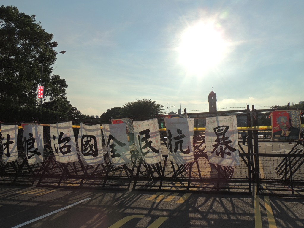 總統府前的拒馬被放上「豺狼治國、人民抗暴」的標語。圖：林怡嫺/攝