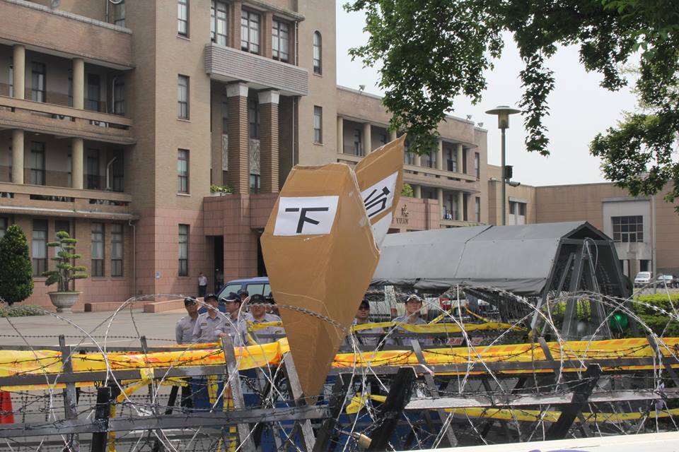 貼著「下台」兩字的大型紙飛機卡在拒馬上下不來。圖：林雨佑/攝