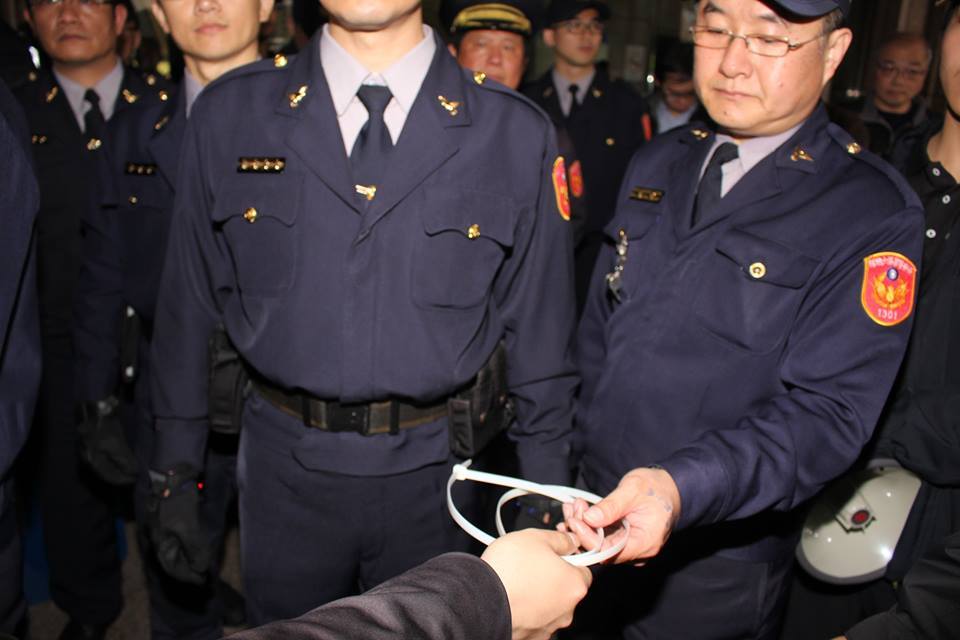 警察從林于倫手上接過束帶。圖：林雨佑/攝