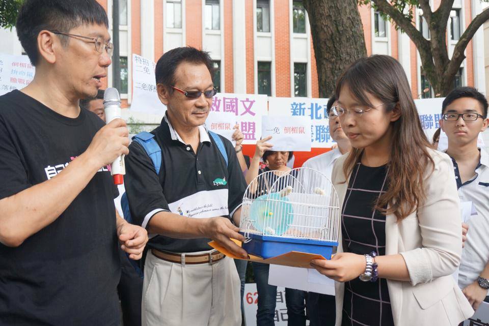 抗議團體將陳情書及裝著白老鼠的籠子交給教育部代表，教育部國民及學前教育署課程及教學科科長李菁菁，以白老鼠隱喻現在12年國教孩子們的窘境。圖2之1：張容瑄/攝