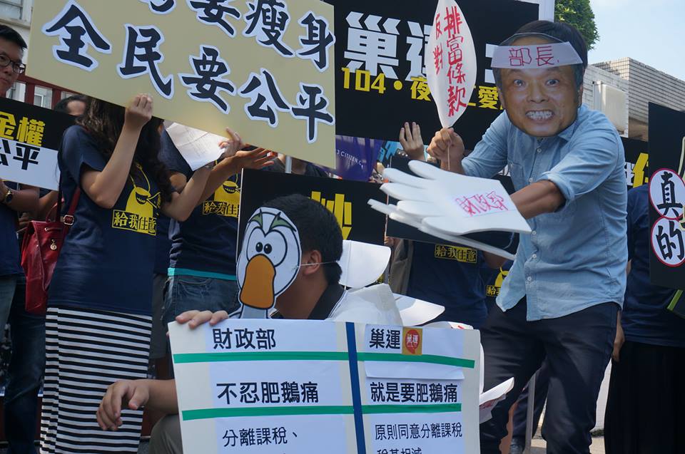 巢運記者會現場行動劇演出，表情猙獰的張盛和從鵝背後拔起一根根名為「排富條款」、「累進稅率」的鵝毛，暗諷財政部「不忍肥鵝痛、專拔瘦鵝毛」。 圖：張容瑄/攝