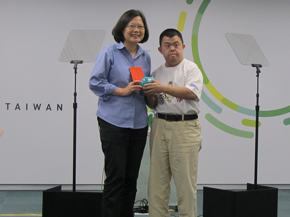 唐氏症患者楊偉仁2日親手把自己工作所賺的鈔票，一張一張折好、塞進小豬撲滿，親自送給民進黨主席暨總統參選人蔡英文。圖：林朝億/攝